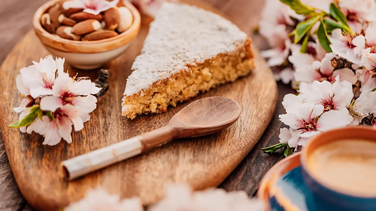 Mallorcan almond cake called Gató adorned with almond blossoms and served with Spanish coffee. Creative color editing with slightly grain added. Part of a series.