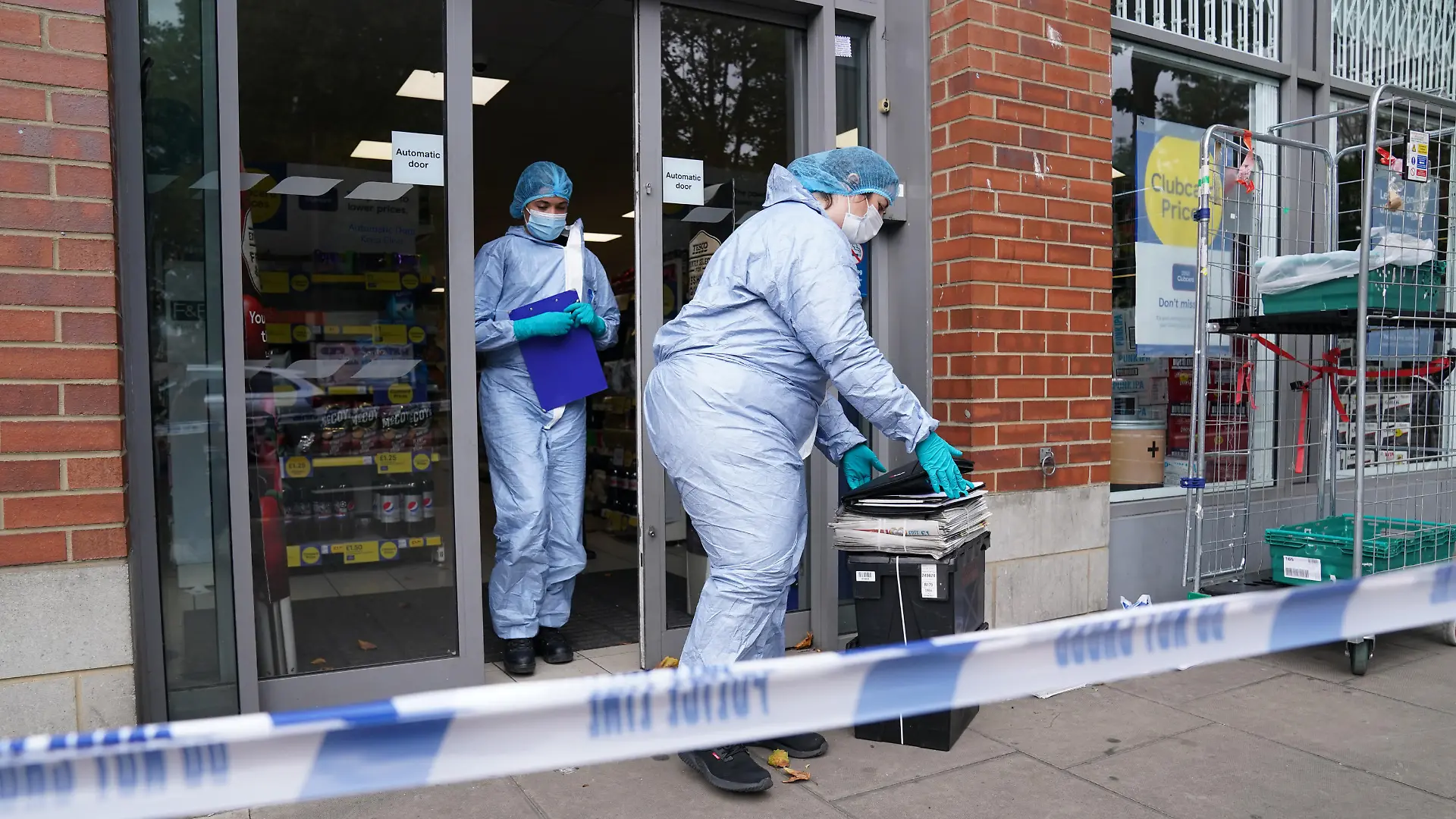 Supermarket food contaminated with syringes. Police officers in forensic suits outside Tesco Express on Fulham Palace Road, west London, which has been closed and a crime scene put in place after a man was arrested on suspicion of contaminating food with a syringe. Police were called on Wednesday evening to a man shouting abuse at people in the street and three supermarkets Tesco Express, Little Waitrose and Sainsbury's Local - have been closed for investigation. Picture date: Thursday August 26, 2021. See PA story POLICE Syringe . Photo credit should read: Jonathan Brady/PA Wire URN:61976487