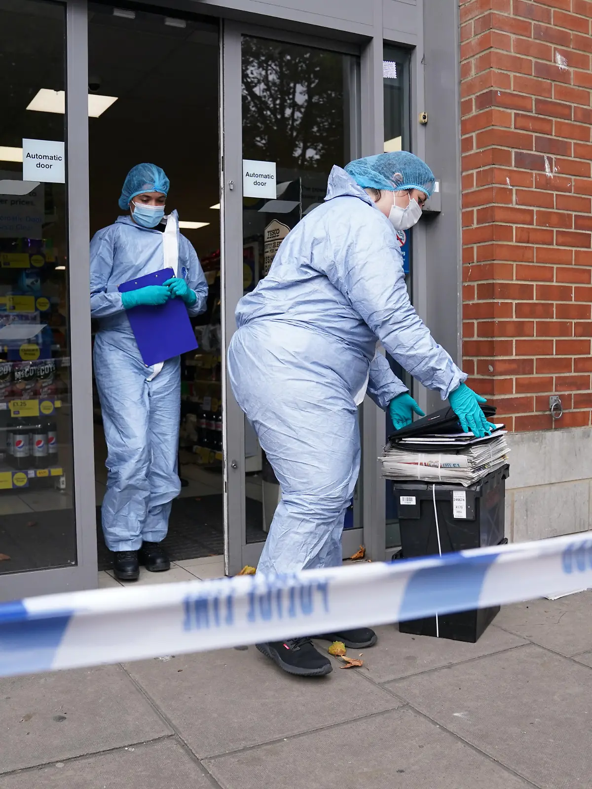 Supermarket food contaminated with syringes. Police officers in forensic suits outside Tesco Express on Fulham Palace Road, west London, which has been closed and a crime scene put in place after a man was arrested on suspicion of contaminating food with a syringe. Police were called on Wednesday evening to a man shouting abuse at people in the street and three supermarkets Tesco Express, Little Waitrose and Sainsbury's Local - have been closed for investigation. Picture date: Thursday August 26, 2021. See PA story POLICE Syringe . Photo credit should read: Jonathan Brady/PA Wire URN:61976487