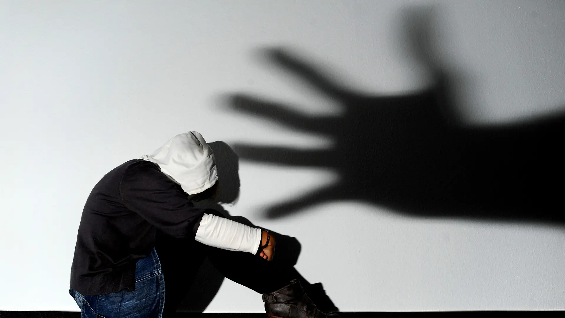 ARCHIV - ILLUSTRATION - Ein Mädchen sitzt am 14.09.2011 vor einer Wand in Hannover, auf der der Schatten einer Hand groß zu sehen ist (Symbolbild zum Thema Opfer von Gewalttaten). Opfer schwerer Straftaten in Niedersachsen sollen eine bessere Unterstützung erhalten. Unter anderem wird landesweit das Angebot der psychosozialen Prozessbegleitung auf den Weg gebracht. Foto: Julian Stratenschulte dpa/lni (zu lni 0302 vom 11.09.2012) +++(c) dpa - Bildfunk+++