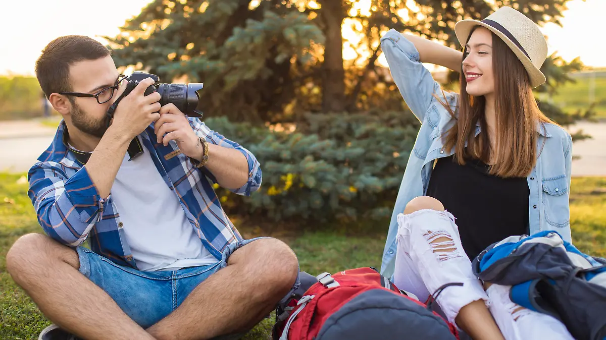 Happy young couple of backpackers in park, taking photographs. Both about 25 years old, Caucasian people.