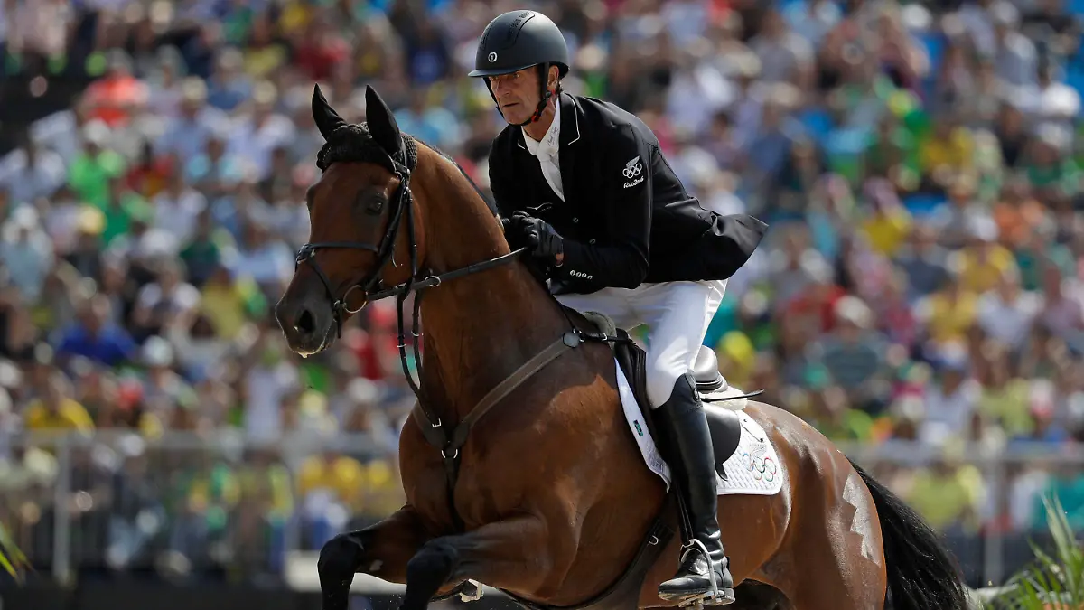 FILE - Mark Todd, of New Zealand, riding Leonidas II, competes in the equestrian eventing team show jumping phase at the 2016 Summer Olympics in Rio de Janeiro, Brazil, on Aug. 9, 2016. Two-time Olympic equestrian champion Mark Todd has temporarily lost his license as a racehorse trainer pending an investigation into a video showing him striking a horse with a branch. The British Horseracing Authority has imposed the interim suspension on the 65-year-old New Zealander preventing him from racing horses in Britain or internationally. (AP Photo/John Locher, File)