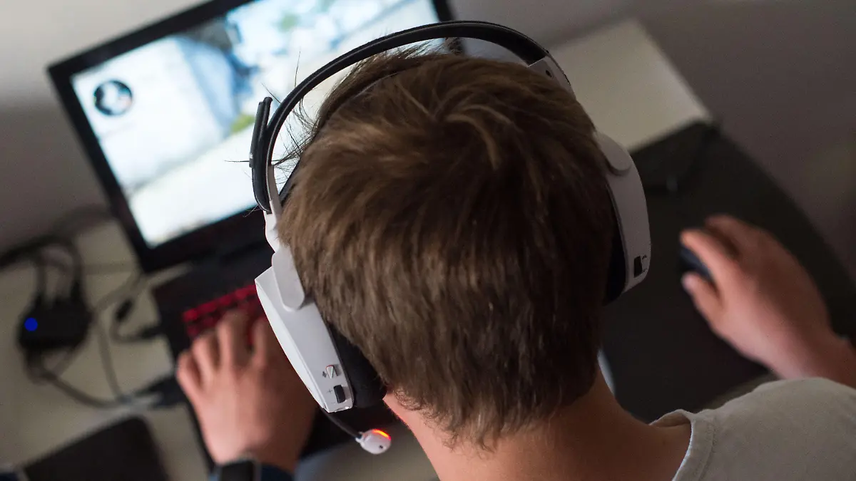 ARCHIV - 17.06.2017, Berlin: ILLUSTRATION - Ein Mann sitzt mit einem Headset vor einem Laptop und spielt ein Online-Computerspiel. Erwachsene und Heranwachsende sollen künftig besser aufgeklärt werden und sich besser schützen können. (zu dpa: «Änderungen zum 1. Mai: Mehr Schutz für Jugendliche online») Foto: Lino Mirgeler/dpa +++ dpa-Bildfunk +++