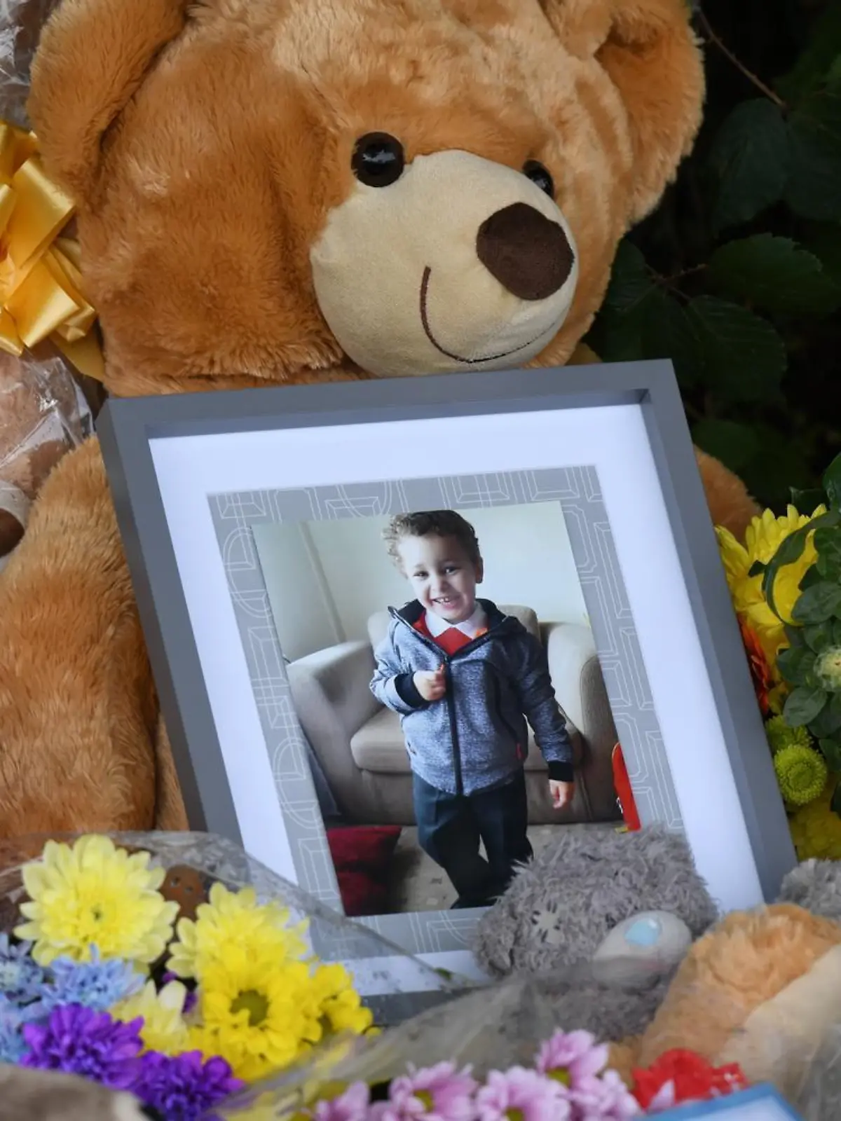 BRIDGEND, WALES - AUGUST 02: A photo of a young boy, believed to be Logan Williamson, (also known as Logan Mwangi) is left amongst the floral tributes near the scene where the body of five-year-old Logan Williamson was found on August 2, 2021 in Sarn, Bridgend, Wales. The body of five-year-old Logan Williamson was found in the Ogmore River in Bridgend in the early hours of Saturday morning. A 39-year-old man, a 30-year-old woman and 13-year-old boy had been arrested on suspicion of murder and remain in custody. (Photo by Matthew Horwood/Getty Images)
