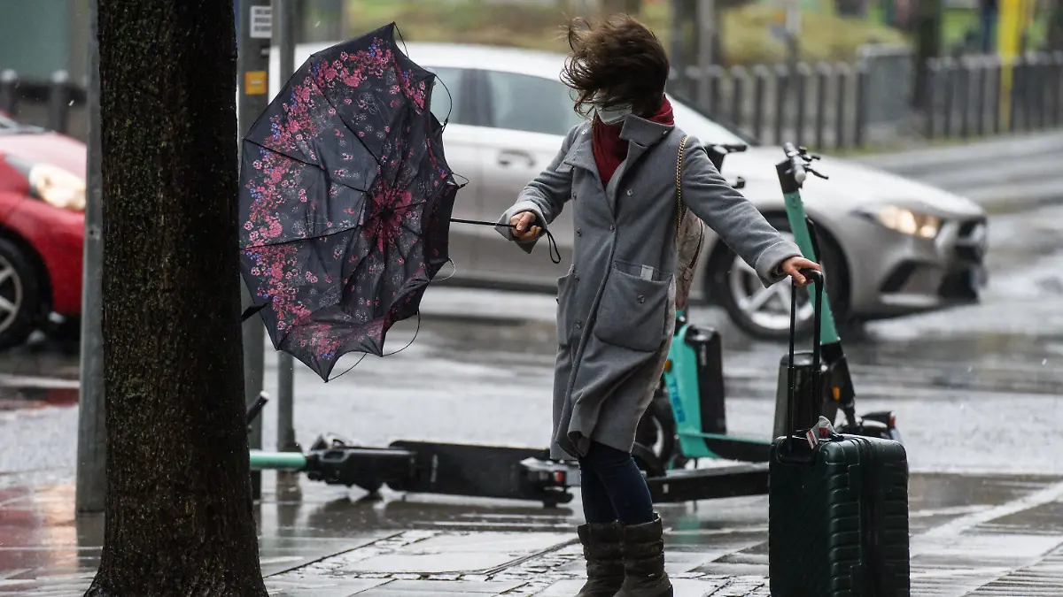 06.02.2022, Hessen, Frankfurt/Main: Eine Frau kämpft mit dem stürmischen Wind, während sie versucht, in der Frankfurter Innenstadt eine Straße zu überqueren. Foto: Frank Rumpenhorst/dpa +++ dpa-Bildfunk +++