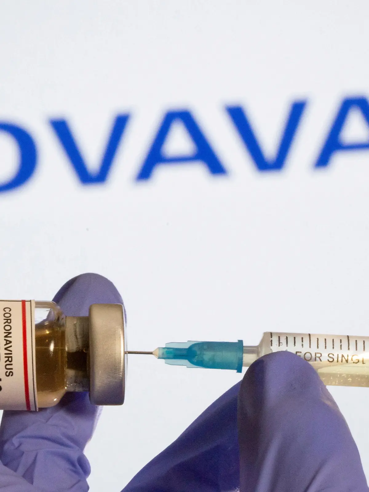 FILE PHOTO: A woman holds a small bottle labeled with a "Coronavirus COVID-19 Vaccine" sticker and a medical syringe in front of displayed Novavax logo in this illustration taken, October 30, 2020. REUTERS/Dado Ruvic/File Photo