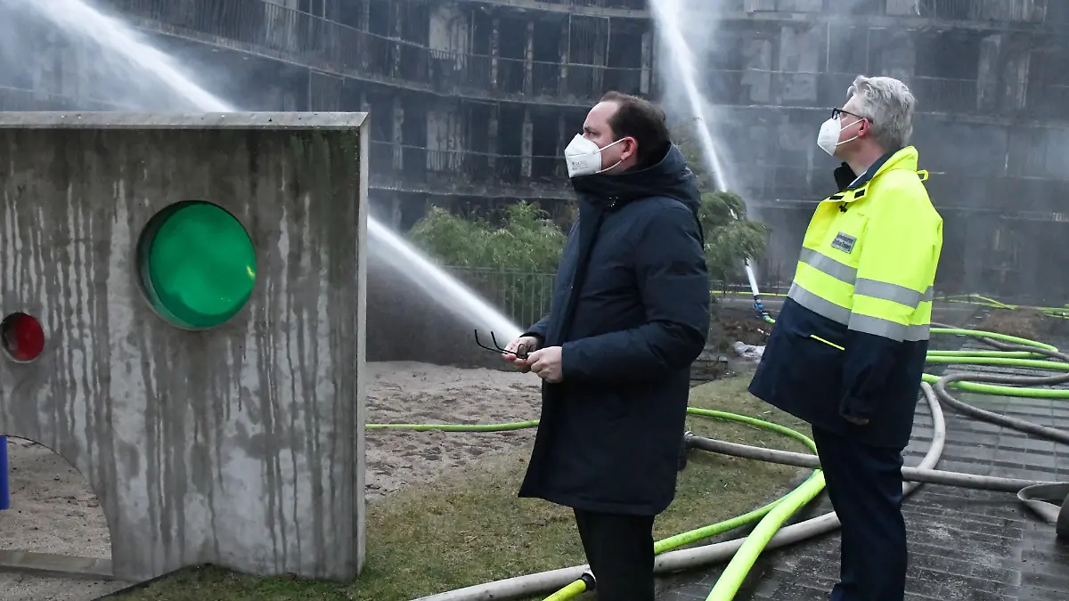 21.02.2022, Nordrhein-Westfalen, Essen: Der Oberbürgermeister der Stadt Essen, Thomas Kufen (CDU l), und Feuerwehrdezernent Christian Kromberg besichtigen einen ausgebrannten Wohnkomplex. Im Westviertel der Stadt stand seit dem frühen Montagmorgen ein ganzer Wohnblock in Flammen. Das Feuer war kurz nach Mitternacht in der Bargmannstraße ausgebrochen. Die Flammen breiteten sich schnell über mehrere Etagen aus. Noch ist unklar, ob Menschen zu Schaden gekommen sind. Foto: Stephan Witte/KDF-TV/dpa +++ dpa-Bildfunk +++