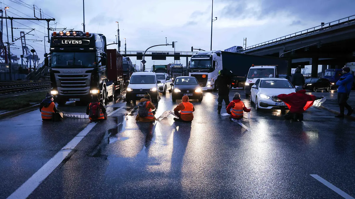 21.02.2022, Hamburg: Klimaaktivisten der Aktion ·Aufstand der letzten Generation· blockieren am Morgen eine Kreuzung am Zollamt Waltershof zur Köhlbrandbrücke und zur Autobahn A7. Foto: Christian Charisius/dpa +++ dpa-Bildfunk +++