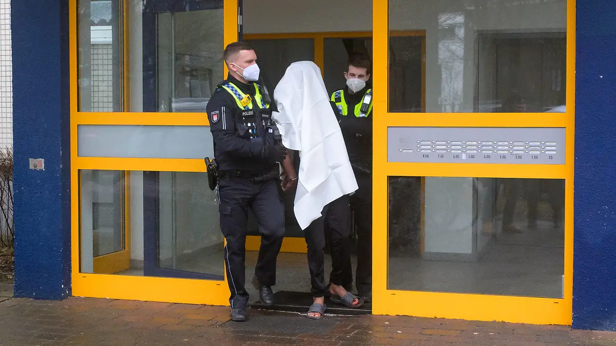 20.02.2022, Hamburg: Polizisten führen einen Tatverdächtigen in Handschellen aus dem Haus. Eine Frau ist am Sonntag mit lebensgefährlichen Stichverletzungen in Hamburg-Niendorf aufgefunden worden. Nach Angaben eines Sprechers hatte eine Anwohnerin Blut im Hausflur gesehen und die Einsatzkräfte verständigt. Den ersten Angaben zufolge sei von einer Auseinandersetzung die Rede gewesen, bei der eine Frau mit einem Messer verletzt worden sei. Foto: Jonas Walzberg/dpa +++ dpa-Bildfunk +++
