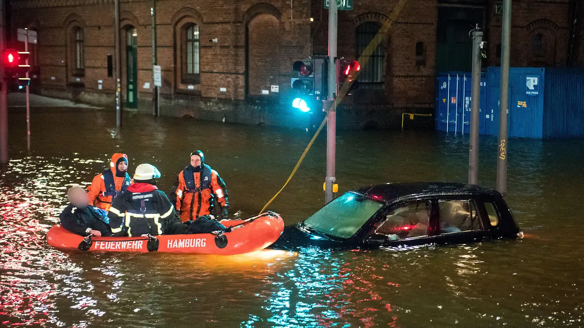 19.02.2022, Hamburg: Feuerwehrleute retten in der Speicherstadt, während einer Sturmflut beim Hochwasser der Elbe, einen Mann aus seinem Auto, der zuvor versehentlich in das Wasser gefahren war. Foto: Daniel Bockwoldt/dpa - ACHTUNG: Person(en) wurde(n) aus rechtlichen Gründen gepixelt +++ dpa-Bildfunk +++