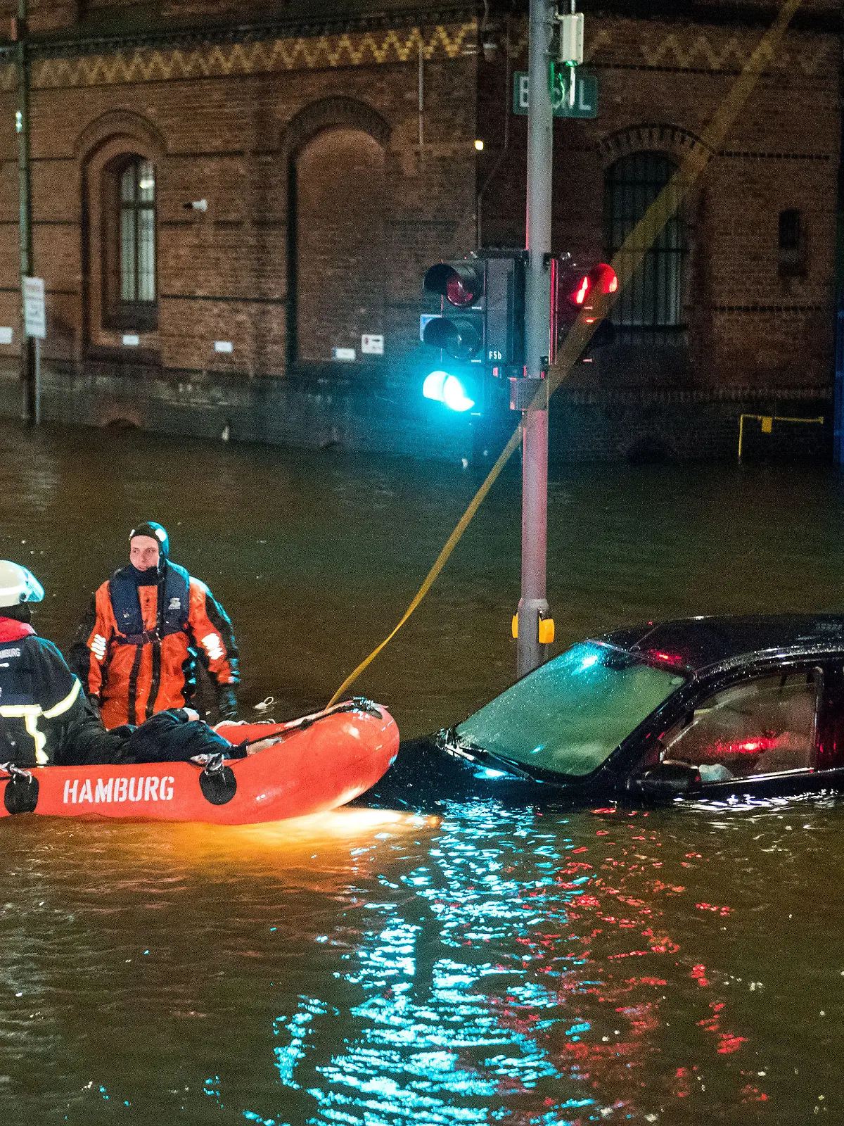 19.02.2022, Hamburg: Feuerwehrleute retten in der Speicherstadt, während einer Sturmflut beim Hochwasser der Elbe, einen Mann aus seinem Auto, der zuvor versehentlich in das Wasser gefahren war. Foto: Daniel Bockwoldt/dpa - ACHTUNG: Person(en) wurde(n) aus rechtlichen Gründen gepixelt +++ dpa-Bildfunk +++