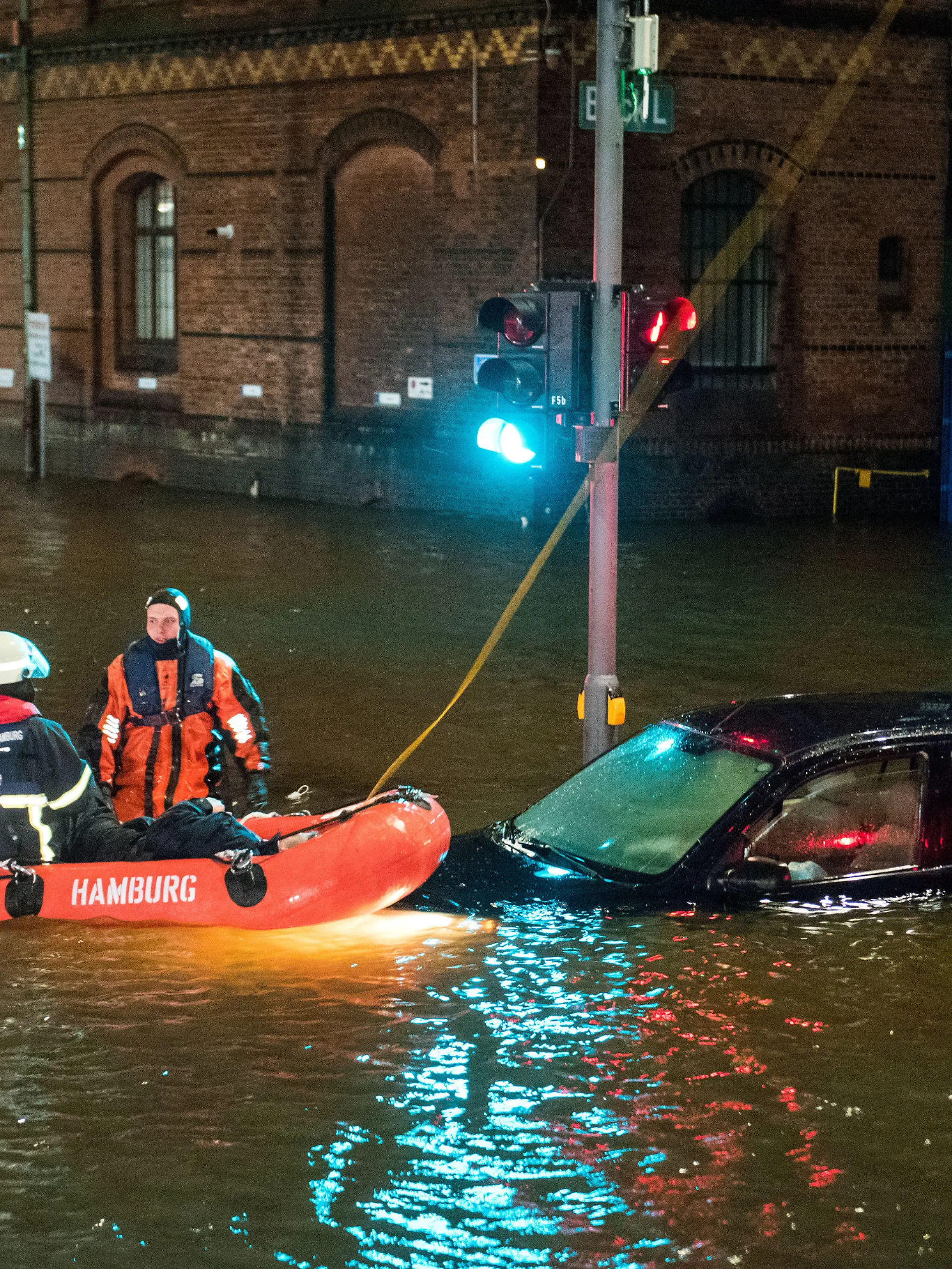 19.02.2022, Hamburg: Feuerwehrleute retten in der Speicherstadt, während einer Sturmflut beim Hochwasser der Elbe, einen Mann aus seinem Auto, der zuvor versehentlich in das Wasser gefahren war. Foto: Daniel Bockwoldt/dpa - ACHTUNG: Person(en) wurde(n) aus rechtlichen Gründen gepixelt +++ dpa-Bildfunk +++