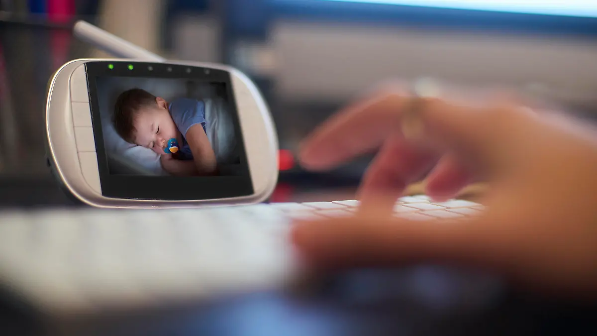 Baby monitor on the desk in home office. Parent is getting on with some work as the baby sleeps.