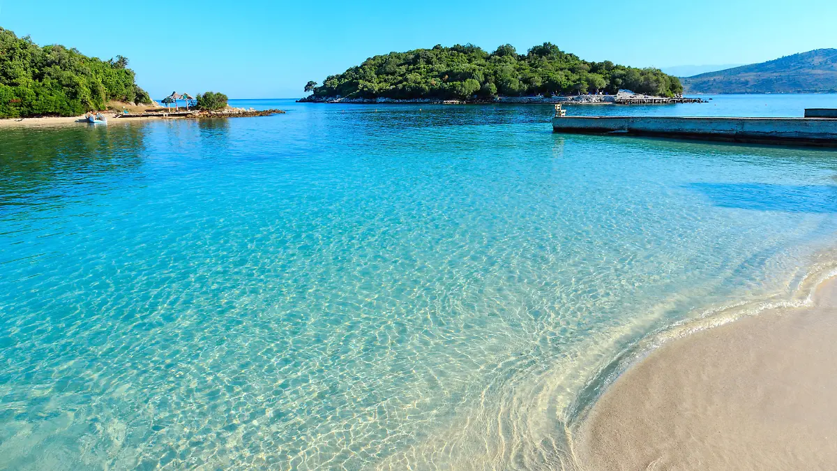 Beautiful Ionian Sea with clear turquoise water and morning summer coast view from beach (Ksamil, Albania). People unrecognizable.