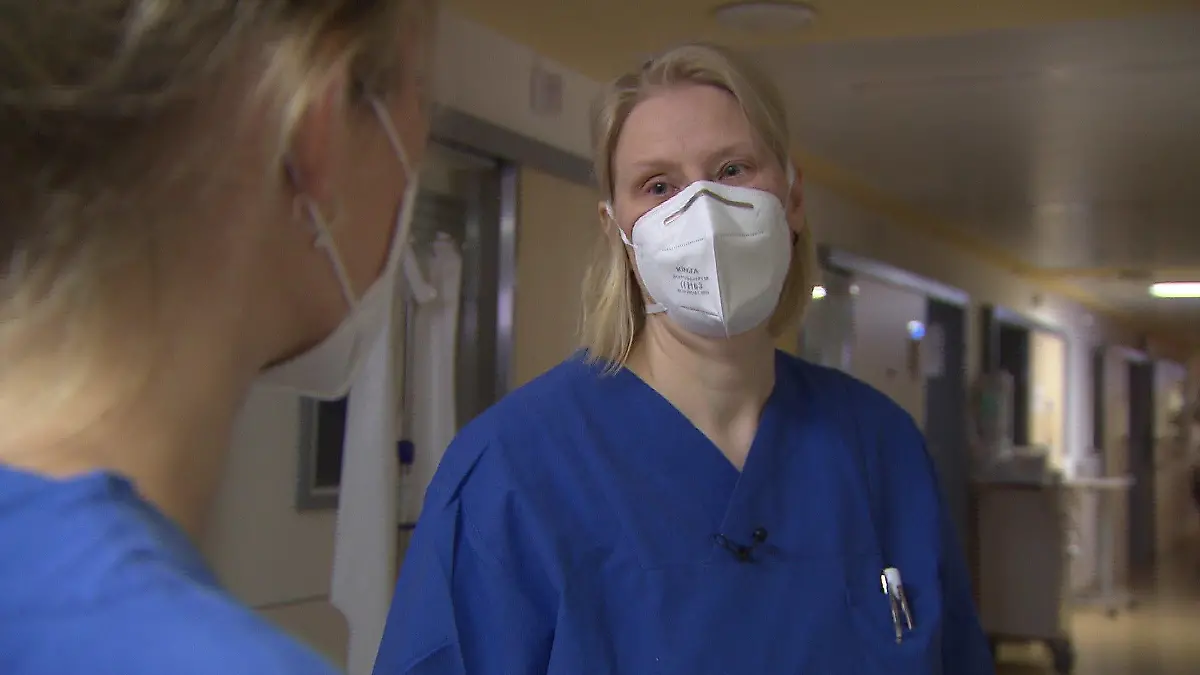 Xenia Franke trägt blaue Arbeitskleidung und ist im Profil abgebildet.