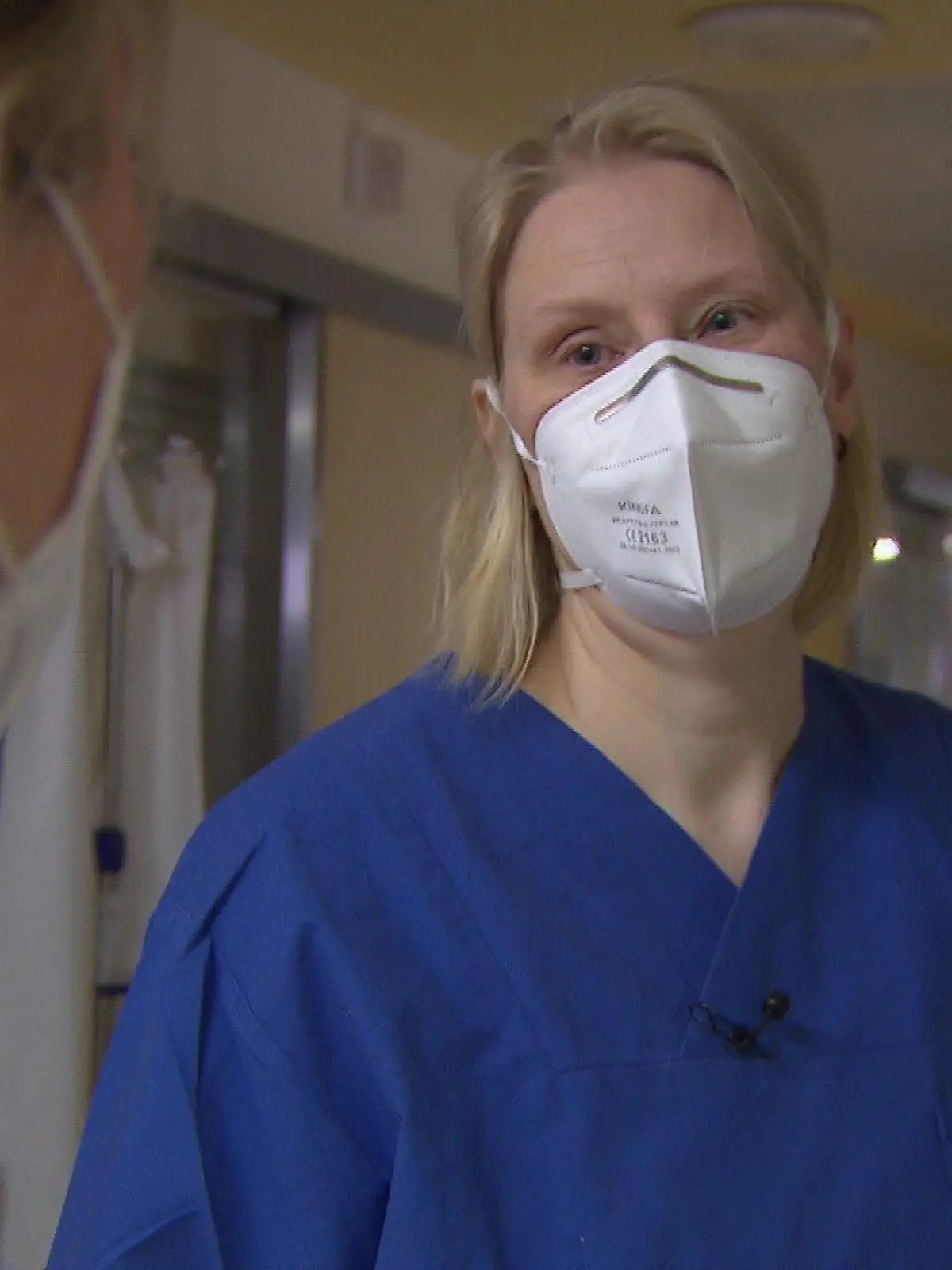 Xenia Franke trägt blaue Arbeitskleidung und ist im Profil abgebildet.