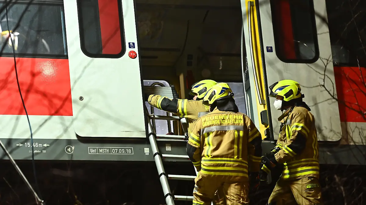 14.02.2022, Bayern, Schäftlarn: Feuerwehrleute befestigen eine Leiter an einem verunfallten S-Bahnwagen. Beim Zusammenstoß zweier S-Bahnen im Landkreis München sind am Montag ein Mensch getötet und mehr als zehn verletzt worden. Es habe eine niedrige zweistellige Zahl an Verletzten gegeben, berichtete ein Sprecher des Münchner Polizeipräsidiums. Foto: Lennart Preiss/dpa +++ dpa-Bildfunk +++