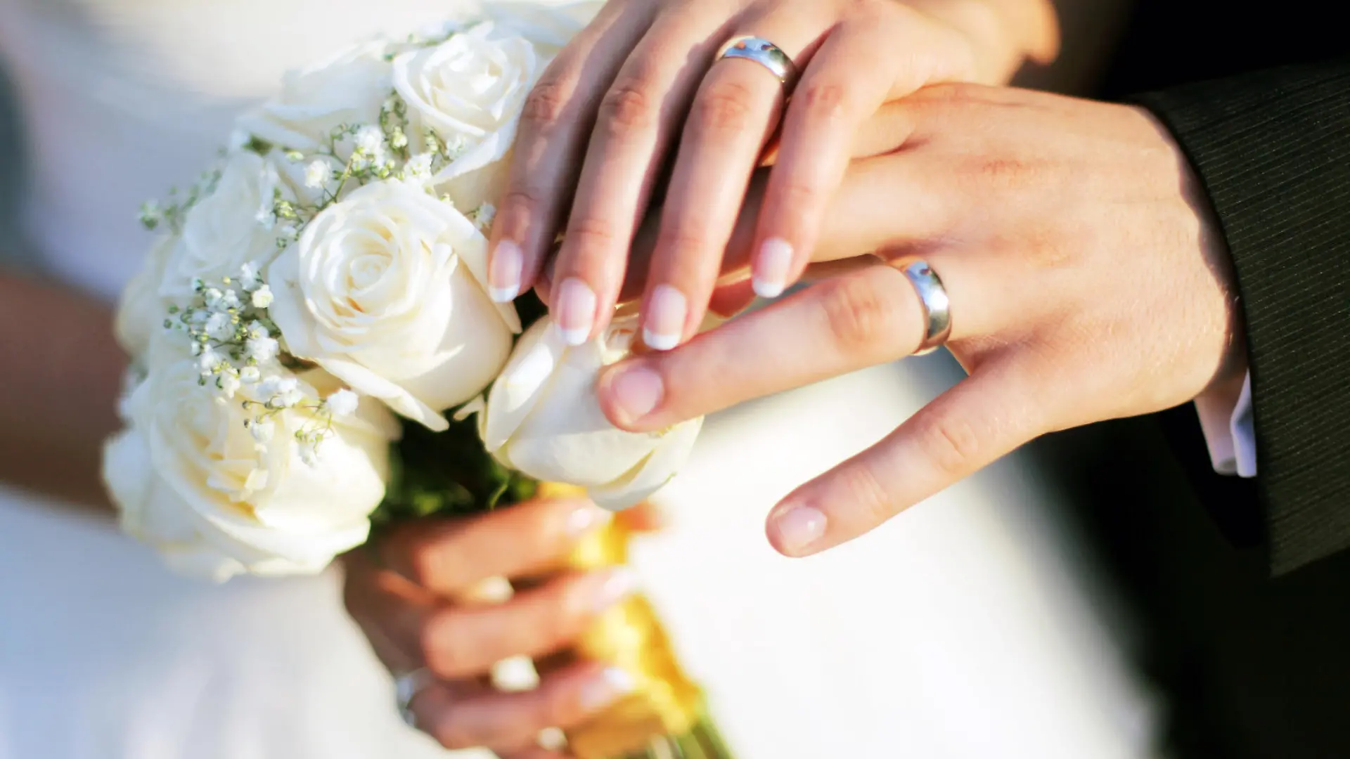 Wedding rings, bouqet and hands holding