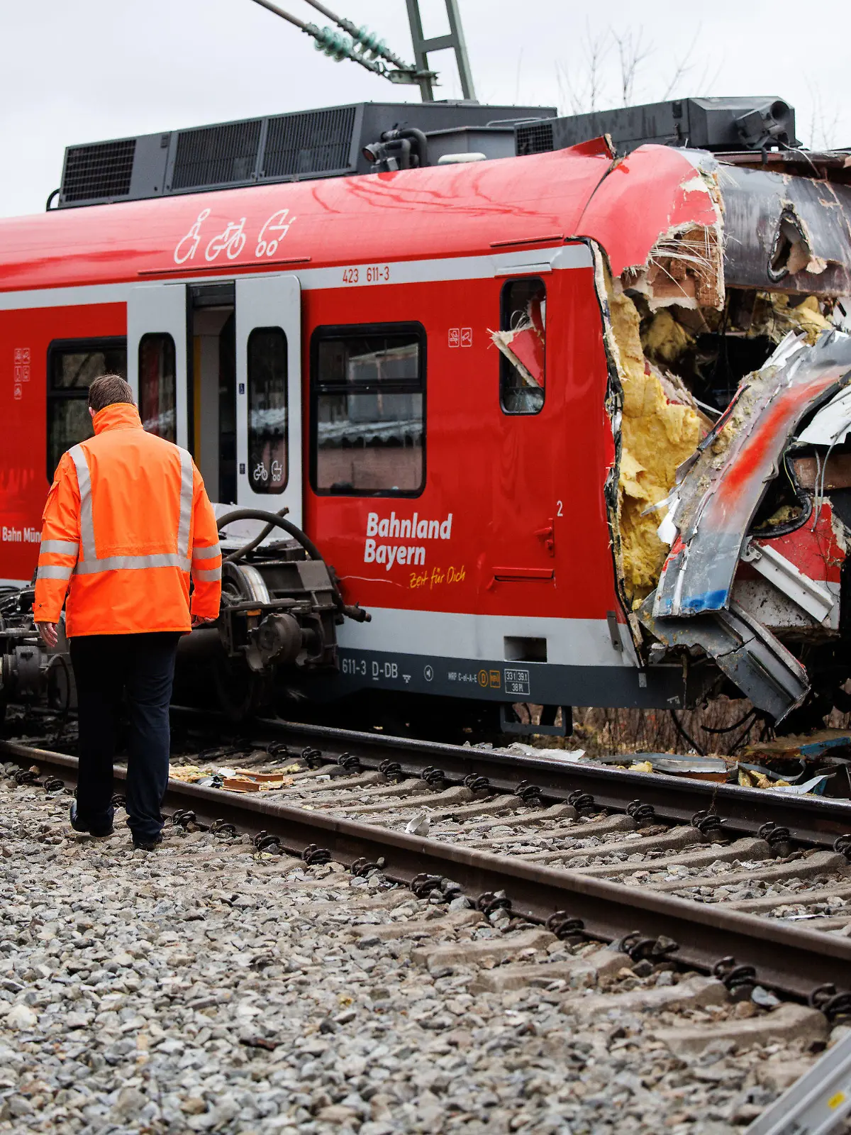 15.02.2022, Bayern, Schäftlarn: Ein Mitarbeiter der Deutschen Bahn geht an der Unfallstelle zweier aufeinander geprallter S-Bahnen in der Nähe des Bahnhofes Ebenhausen-Schäftlarn vorüber. Beim Zusammenstoß zweier S-Bahnen im Landkreis München sind am Montag ein Mensch getötet und mehr als zehn verletzt worden. Foto: Matthias Balk/dpa +++ dpa-Bildfunk +++