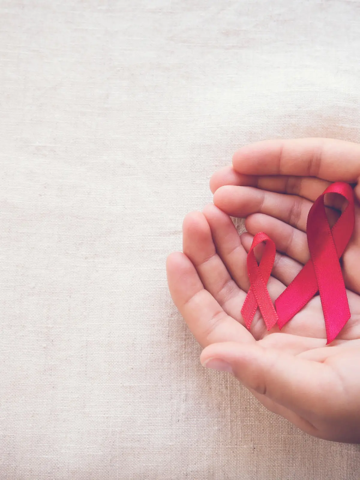 hands holding Red Ribbons on toning background, HIV/AIDS, Anosmia, Heart disease,Epidermolysis bullosa and Vasculitis awareness