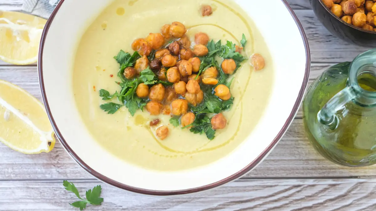 Potato and leek soup with spicy chickpeas and olive oil on the table