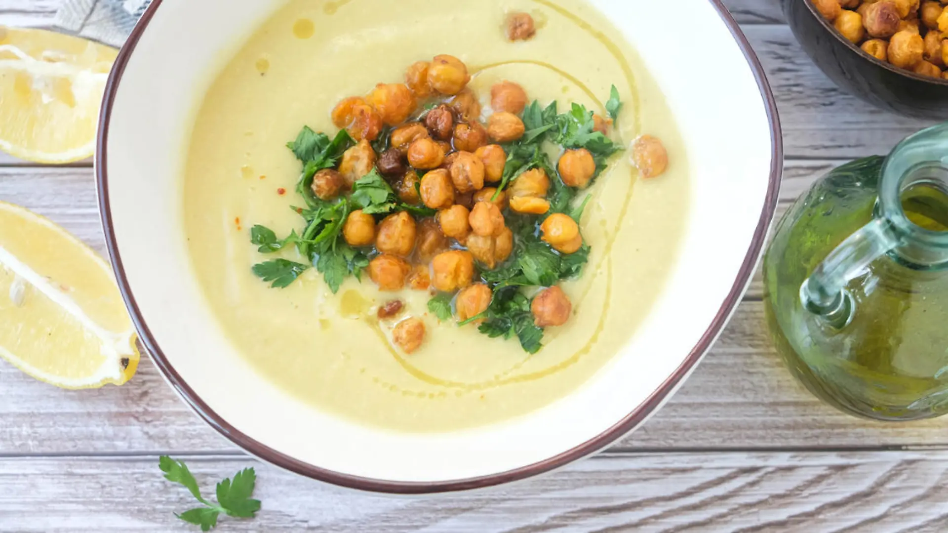 Potato and leek soup with spicy chickpeas and olive oil on the table