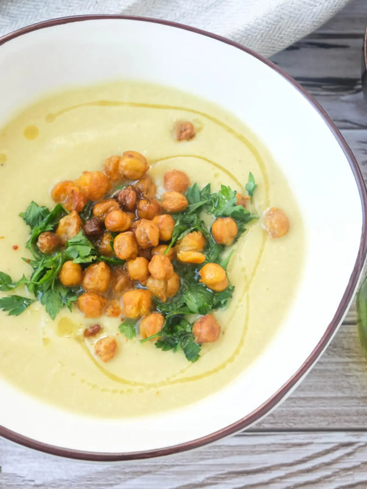 Potato and leek soup with spicy chickpeas and olive oil on the table