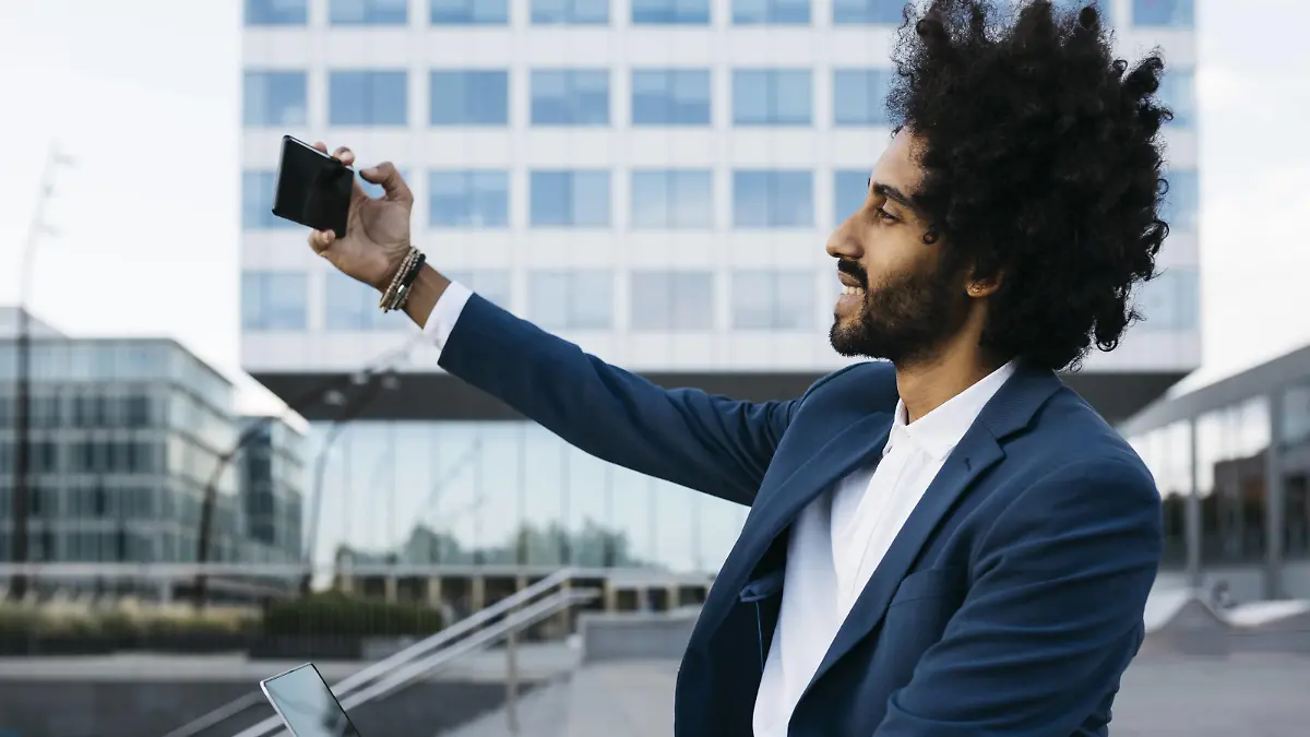 Spain, Barcelona, smiling young businessman taking a selfie in the city model released Symbolfoto PUBLICATIONxINxGERxSUIxAUTxHUNxONLY JRFF02069