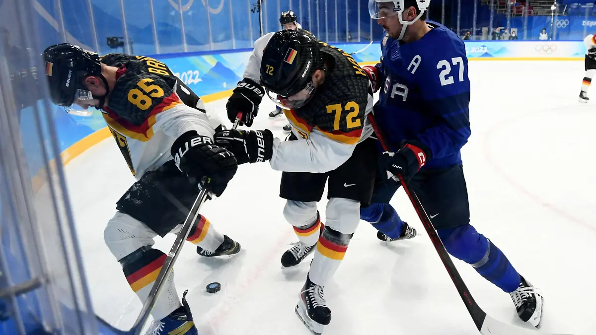 2022 Beijing Olympics - Ice Hockey - Men's Prelim. Round - Group A - United States v Germany - Wukesong Sports Centre, Beijing, China - February 13, 2022. Noah Cates of the United States in action with Marcel Brandt of Germany and Dominik Kahun of Germany. REUTERS/Annegret Hilse