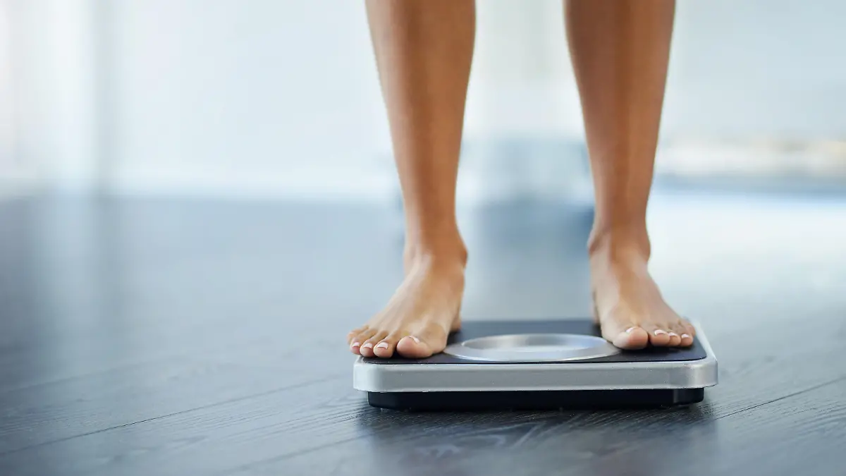 Shot of an unrecognizable woman weighing herself at home
