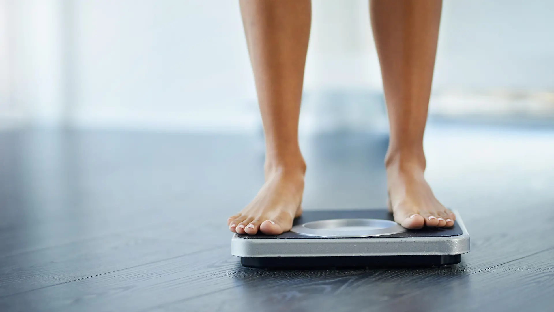 Shot of an unrecognizable woman weighing herself at home