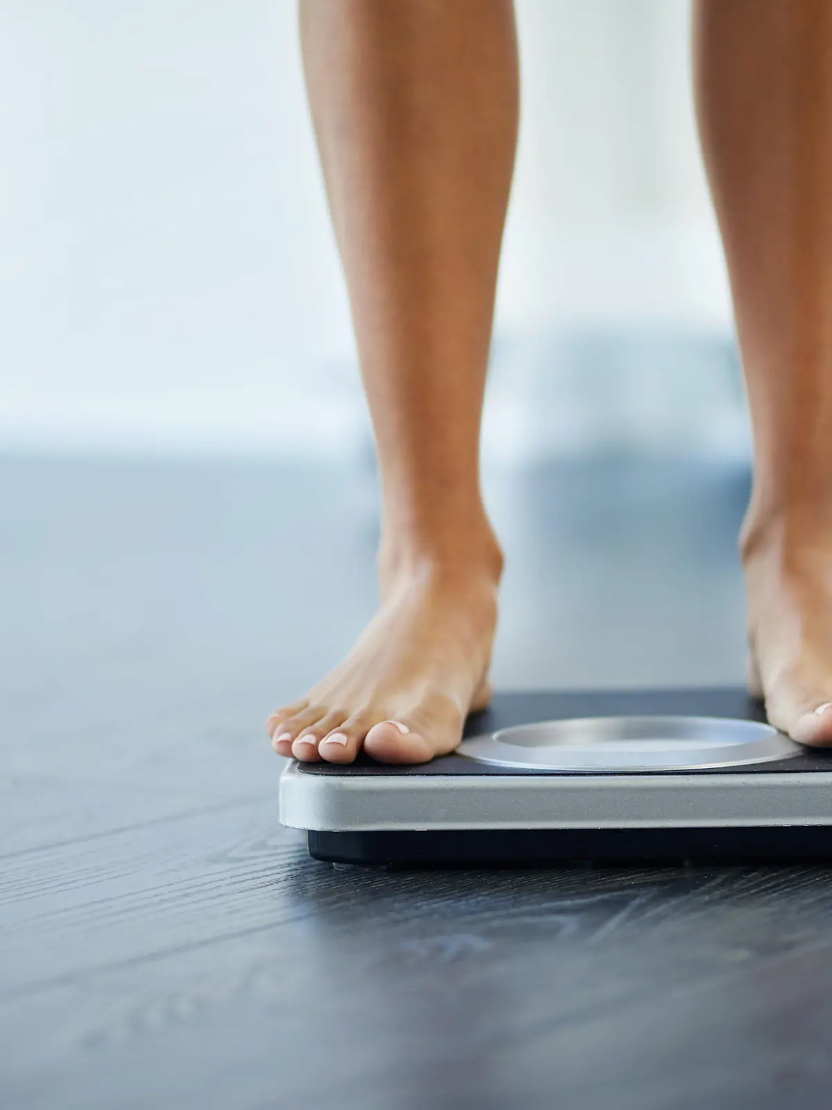 Shot of an unrecognizable woman weighing herself at home