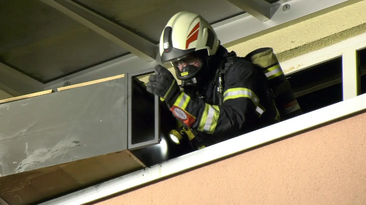 14.02.2022, Hessen, Darmstadt: Ein Feuerwehrmann wirft Mobiliar vom Balkon der brennenden Wohnung. Ein Mann ist bei einem Wohnungsbrand in Darmstadt lebensgefährlich verletzt worden. Nach ersten Erkenntnissen entstand das Feuer am Sonntag an einem Ethanolofen, wie die Polizei mitteilte. Foto: Alexander Keutz/Keutz TV/dpa +++ dpa-Bildfunk +++