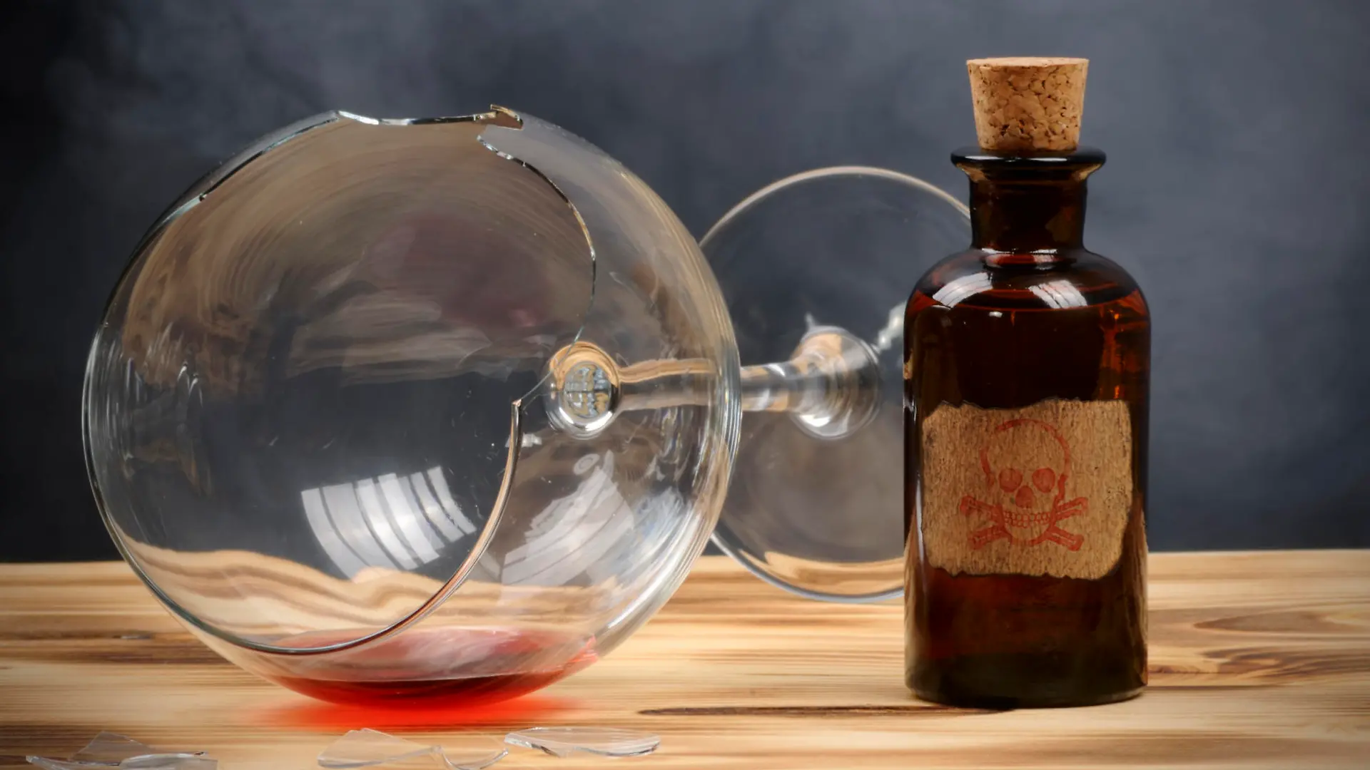 A broken wine glass and a vintage poison bottle.