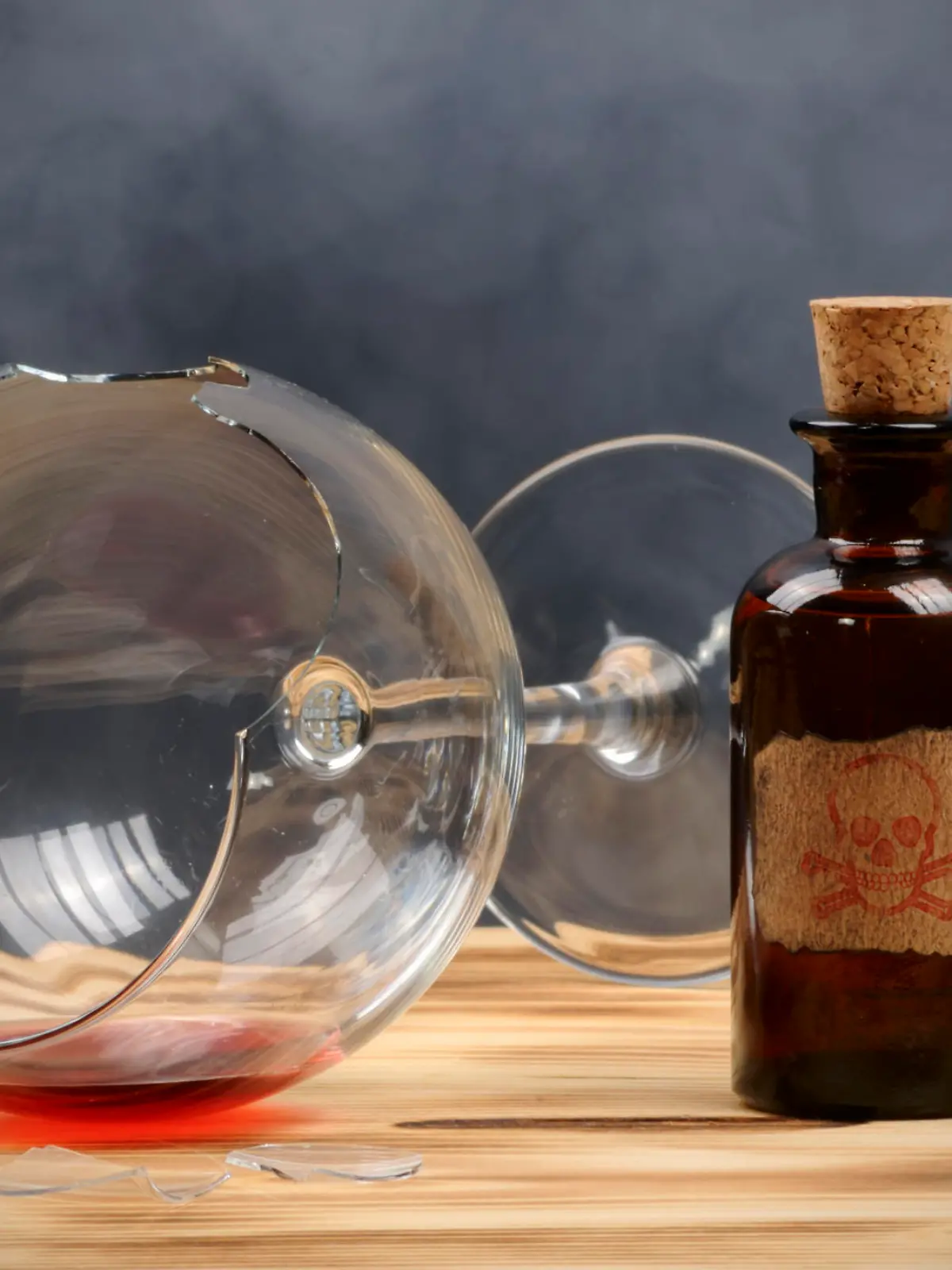 A broken wine glass and a vintage poison bottle.