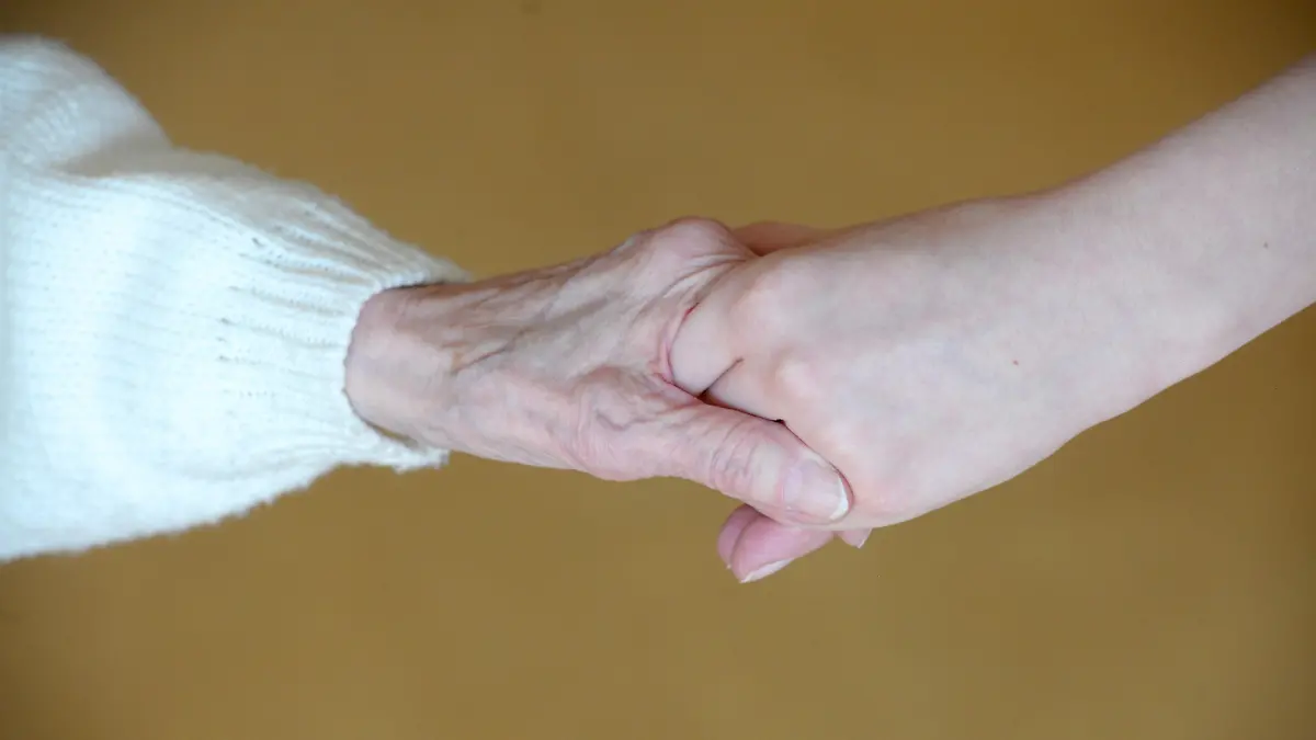 Die Hand einer Pflegeheimbewohnerin (l) greift nach der jüngeren Hand einer Pflegekraft in dem Pflegeheim "Heiterblick", aufgenommen am 24.02.2011 in Leipzig. Foto: Peter Endig