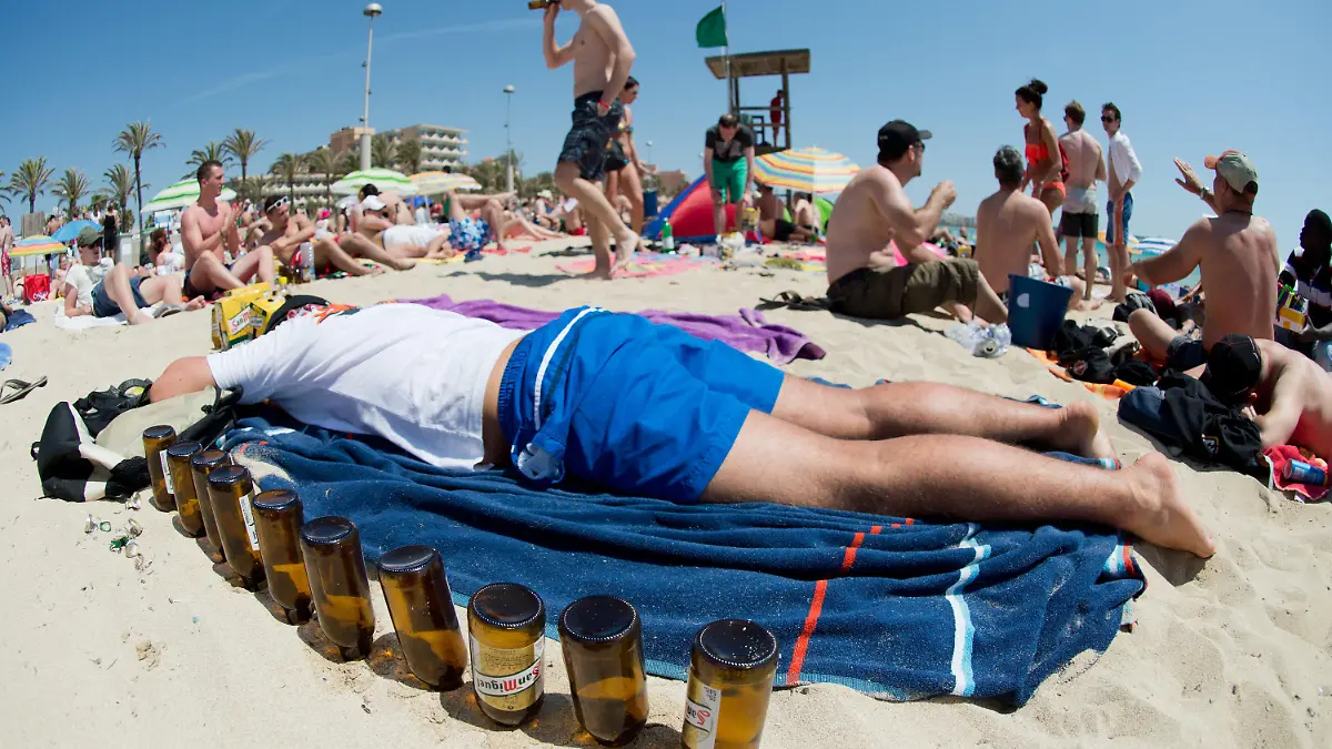 ARCHIV - Ein Tourist liegt am 06.06.2013 schlafend auf einer Luftmatratze neben leeren Bierflaschen am Strand von Arenal auf der Mittelmeerinsel Mallorca (Spanien). Foto: Julian Stratenschulte/dpa (zu dpa «Saufgelage am Ballermann werden verboten» vom 08.03.2016) +++(c) dpa - Bildfunk+++