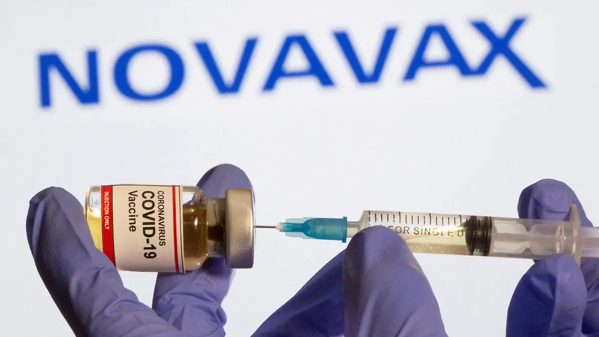 FILE PHOTO: A woman holds a small bottle labeled with a "Coronavirus COVID-19 Vaccine" sticker and a medical syringe in front of displayed Novavax logo in this illustration taken, October 30, 2020. REUTERS/Dado Ruvic/File Photo