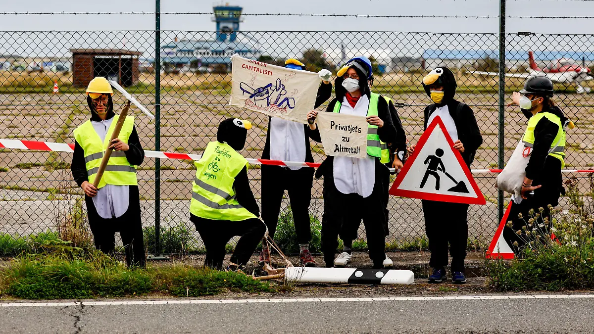 25.08.2023, Schleswig-Holstein, Tinnum/Sylt: Als Pinguine verkleidete Aktivistin der Gruppe ·Am Boden bleiben· versuchen den Flughafen auf Sylt zu blockieren. Foto: Axel Heimken/dpa +++ dpa-Bildfunk +++