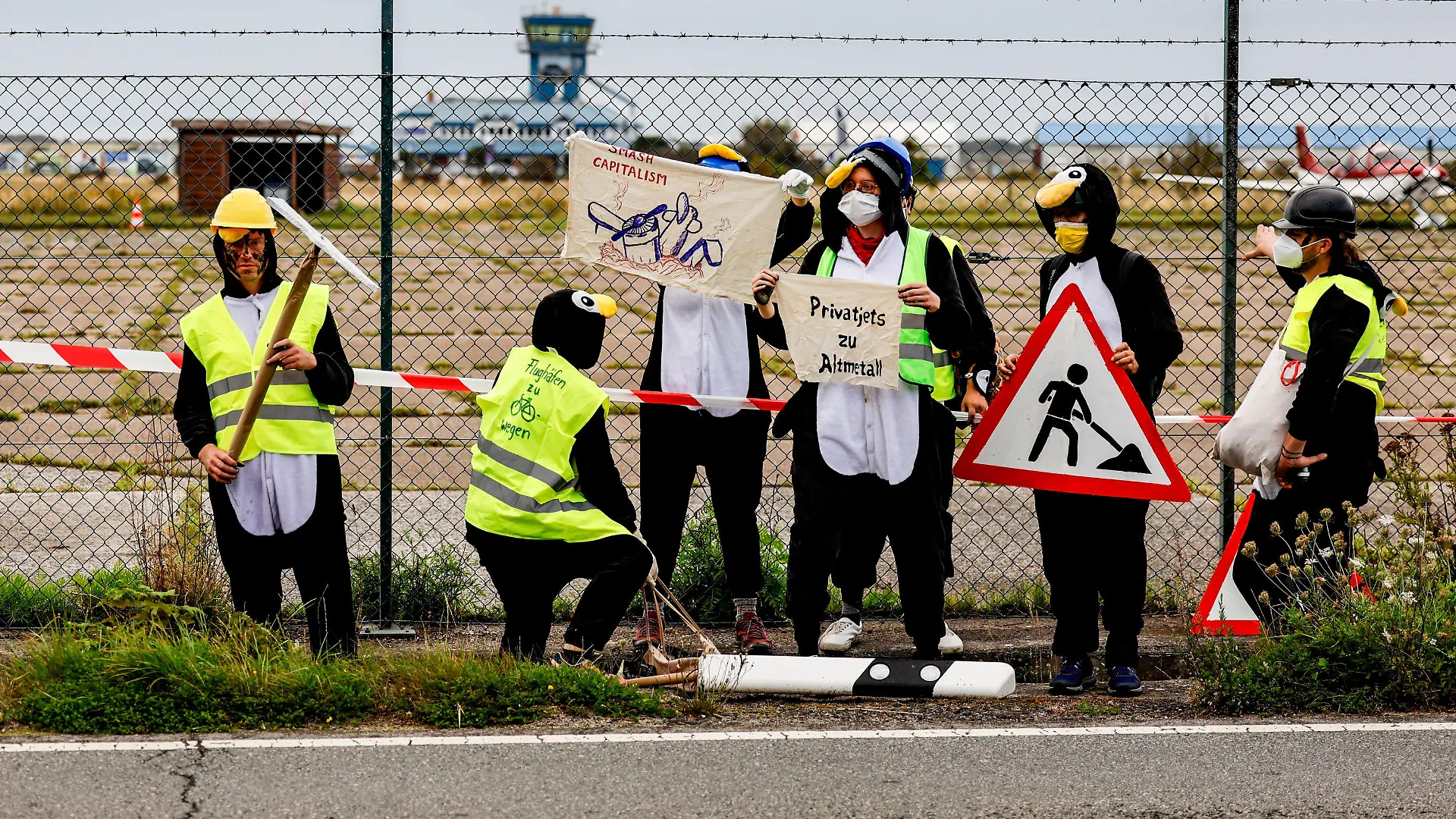 25.08.2023, Schleswig-Holstein, Tinnum/Sylt: Als Pinguine verkleidete Aktivistin der Gruppe ·Am Boden bleiben· versuchen den Flughafen auf Sylt zu blockieren. Foto: Axel Heimken/dpa +++ dpa-Bildfunk +++