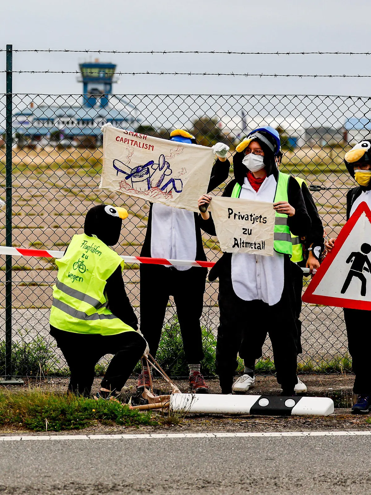 25.08.2023, Schleswig-Holstein, Tinnum/Sylt: Als Pinguine verkleidete Aktivistin der Gruppe ·Am Boden bleiben· versuchen den Flughafen auf Sylt zu blockieren. Foto: Axel Heimken/dpa +++ dpa-Bildfunk +++