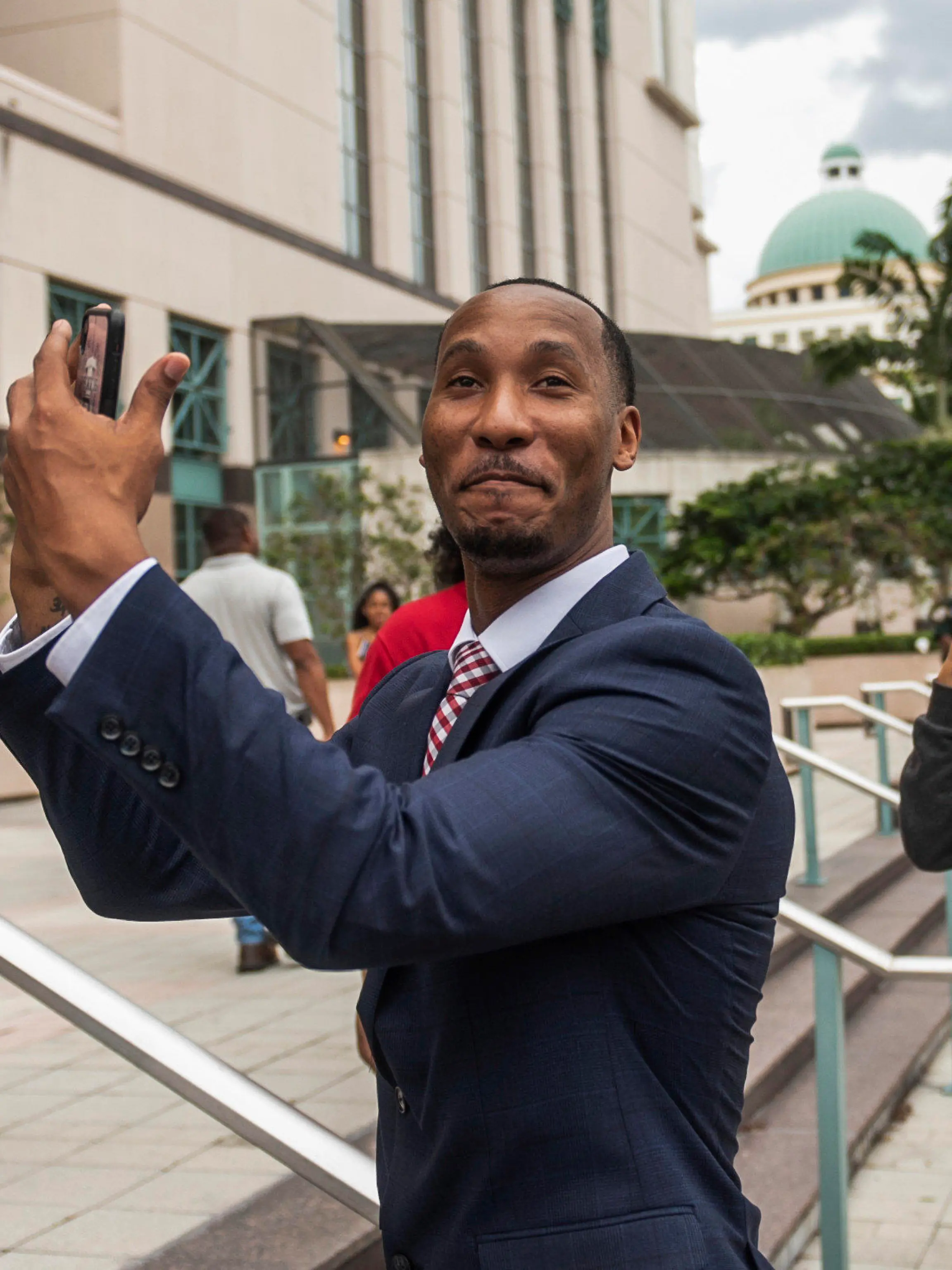 Travis Rudolph mimes catching a football while standing on the steps of the Palm Beach County Courthouse after a jury acquitted him of all charges in a fatal shooting in 2021, Wednesday, June 7, 2023, in West Palm Beach, Fla. (Andres Leiva/The Palm Beach Post via AP)