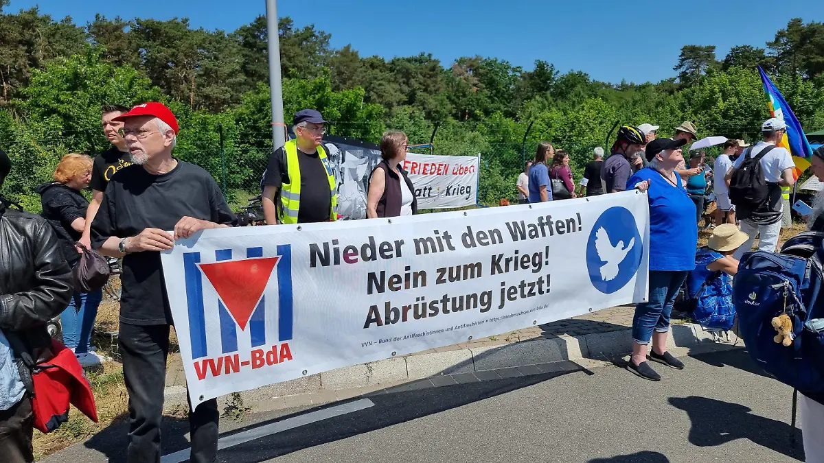 10.06.2023, Niedersachsen, Wunstorf: Menschen halten ein Banner mit der Aufschrift "Nieder mit den Waffen! Nein zum Krieg! Abrüstung jetzt!" während einer Demonstration vor dem Fliegerhorst in Wunstorf gegen das internationale Luftwaffen-Manöver «Air Defender 2023». Foto: Fernando Martinez/dpa +++ dpa-Bildfunk +++