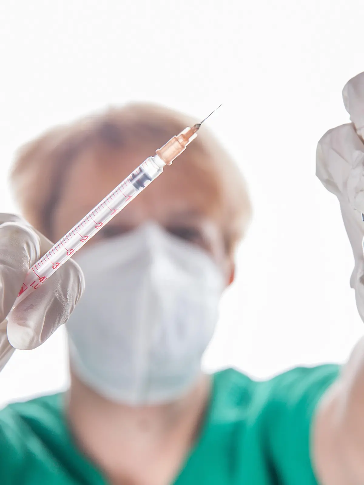 Bamberg, Deutschland 22. November 2021: Eine Person mit Schutzhandschuhen hat mit Hilfe einer Impfspritze eine Impfdosis mit dem mRNA-Impfstoff Comirnaty, BNT162b2, Biontech / Pfizer aus einer Ampulle für die Erstimpfung- Zweitimpfung oder Boosterimpfung aufgezogen gegen das Coronavirus Covid 19.