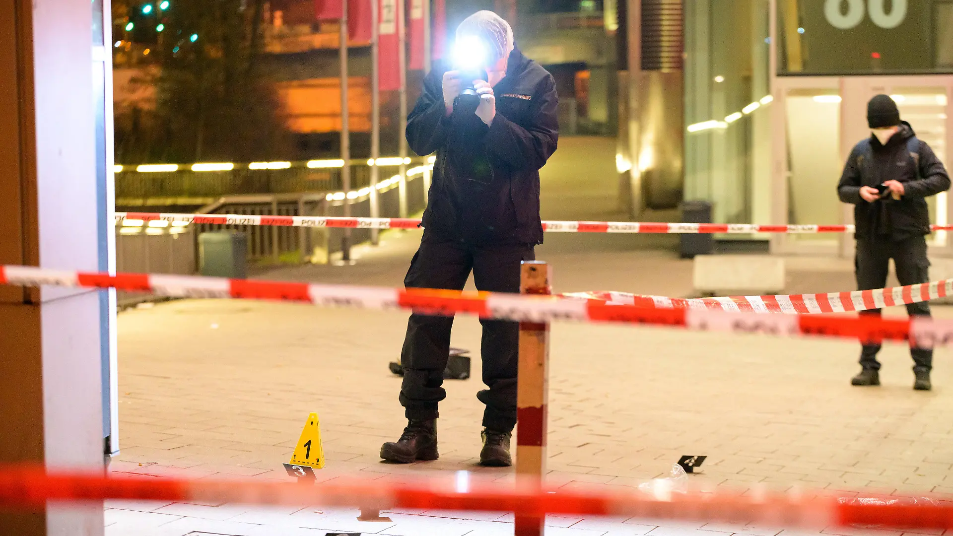 12.02.2022, Hamburg: Kriminaltechniker ermitteln am abgesperrten Fundort des Verletzten vor einem Einkaufszentrum. Bei einer Messerattacke in Hamburg-Harburg ist ein Mann nach Polizeiangaben «nicht unerheblich» verletzt worden. Die Mordkommission ermittele, sagte ein Sprecher des Lagezentrums der Polizei nach der Tat am Samstagabend. Foto: Jonas Walzberg/dpa +++ dpa-Bildfunk +++