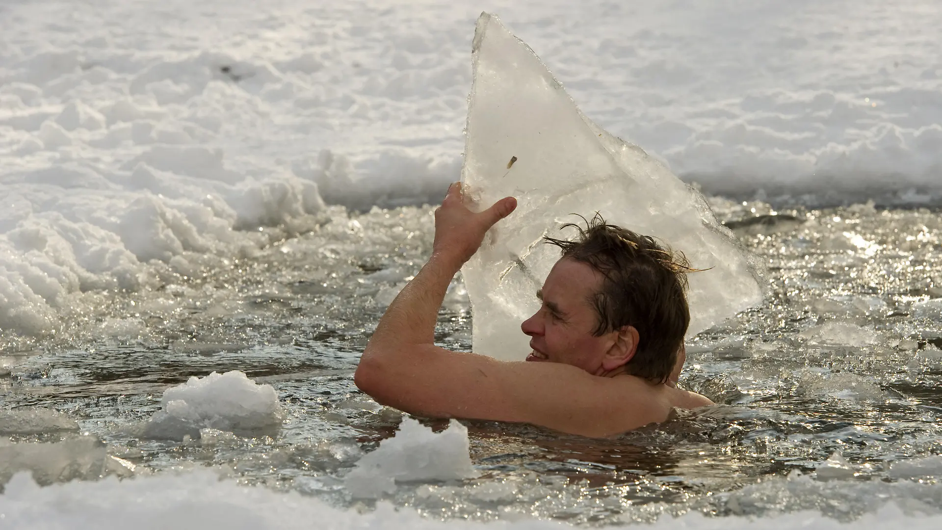 Götz badet am Sonntag (31.01.2010) bei Temperaturen um Minus sieben Grad in einem Eisloch des Schlachtensee in Berlin und wirft Eisbrocken aus dem Wasser. Seit elf Jahren sucht er das kühle Nass so oft wie möglich auf, egal bei welchen Temperaturen und gesund ist er nach eigenen Angabe immer. Foto: Arno Burgi dpa/lbn +++(c) dpa - Bildfunk+++