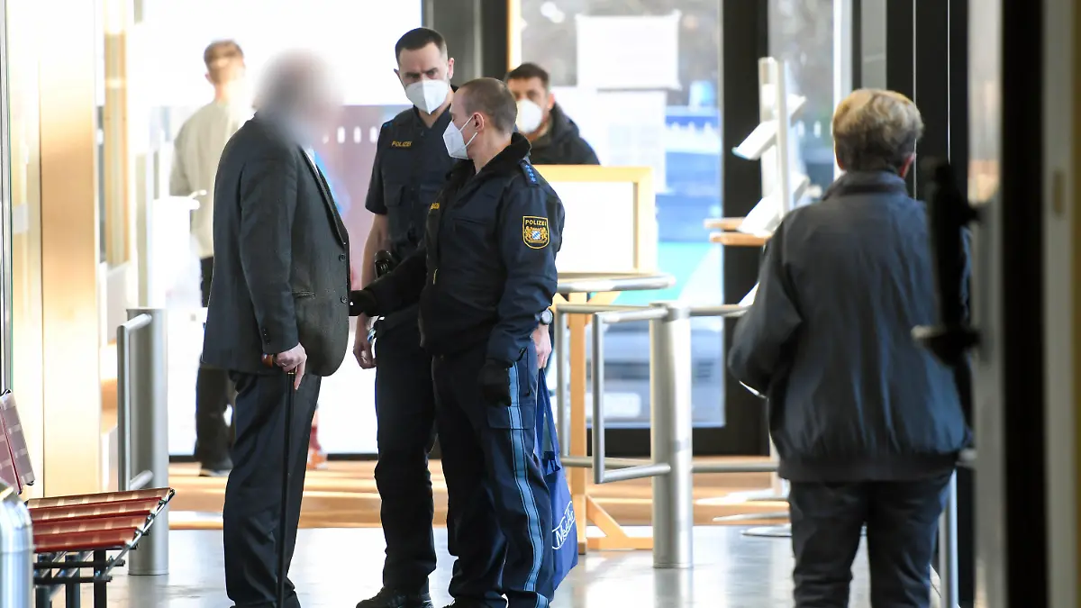 10.02.2022, Bayern, Traunstein: Der Angeklagte (vorne, l) wird kurz vor Prozessauftakt von Polizisten in das Landgericht Traunstein gebracht. Der Mann soll sich als Arzt ausgegeben und hunderte Patienten gegen Corona geimpft haben. Foto: Tobias Hase/dpa - ACHTUNG: Der Angeklagte wurde auf Wunsch seiner Anwältin gepixelt +++ dpa-Bildfunk +++
