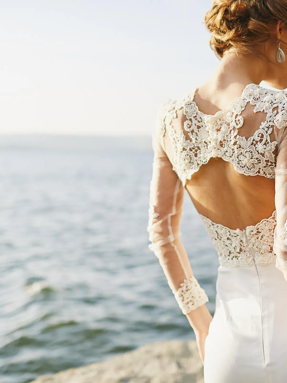 Frau in Hochzeitskleid am Strand.