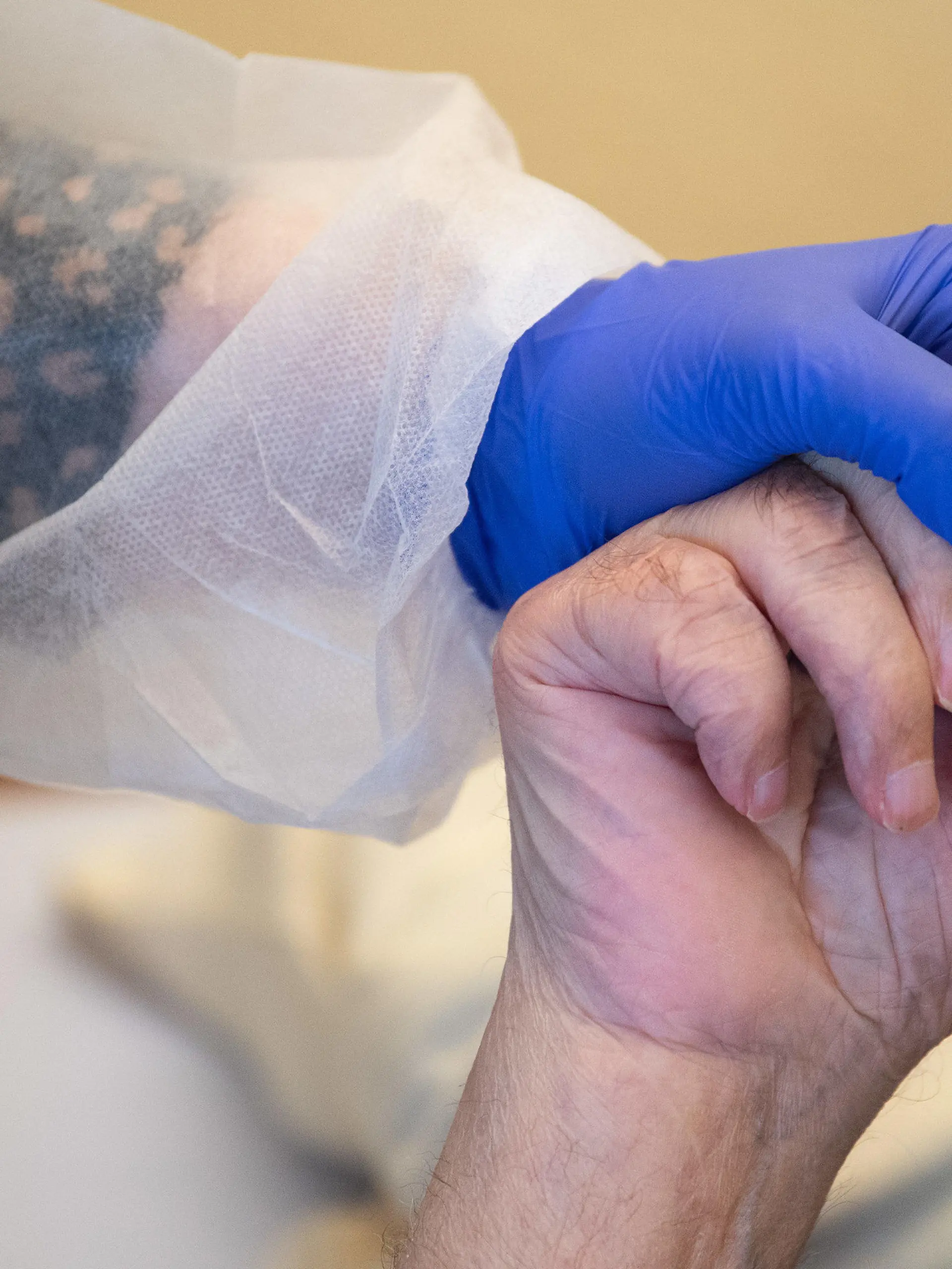 ARCHIV - 18.11.2020, Baden-Württemberg, Tübingen: Eine Altenpflegerin in Schutzkleidung hält die Hand eines Bewohners. Die Altenpflegerinnen und -pfleger in Deutschland können auf bundesweit einheitliche und in vielen Fällen höhere Bezahlung hoffen. (Zu dpa: ««Stunde der Wahrheit» für höheren Pflegelohn») Foto: Sebastian Gollnow/dpa +++ dpa-Bildfunk +++