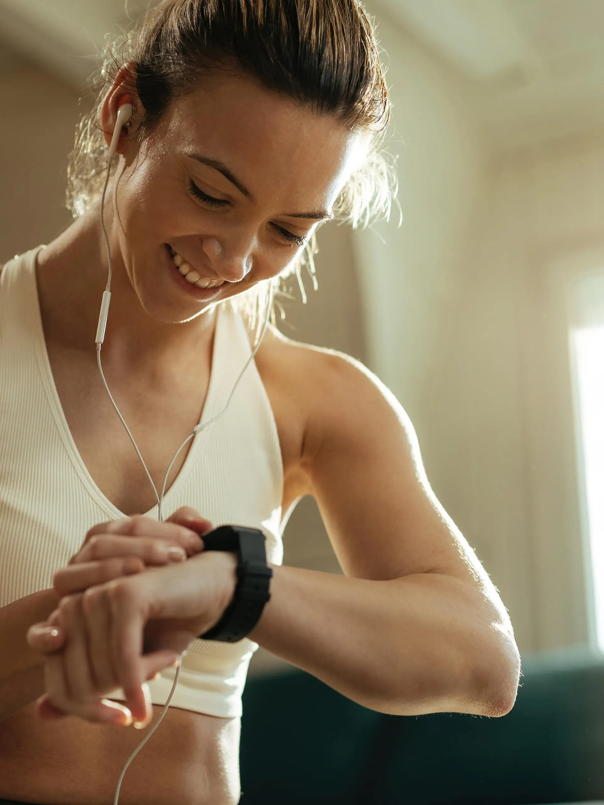 Happy athletic woman measuring heart rate on smart watch while resting after exercising at home.